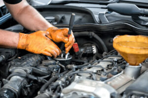 A man wearing gloves repairs a car engine, focused on the intricate mechanical components.